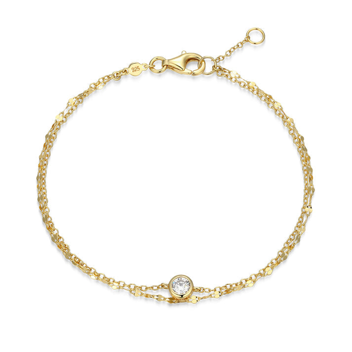 A double strand gold bracelet with one bezel set diamond on one chain on a white background