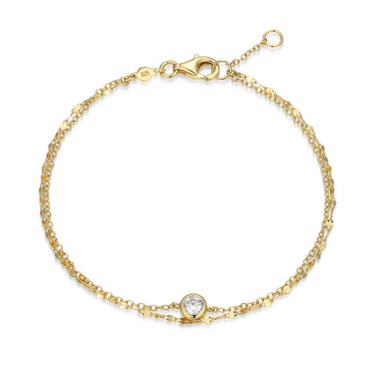 A double strand gold bracelet with one bezel set diamond on one chain on a white background