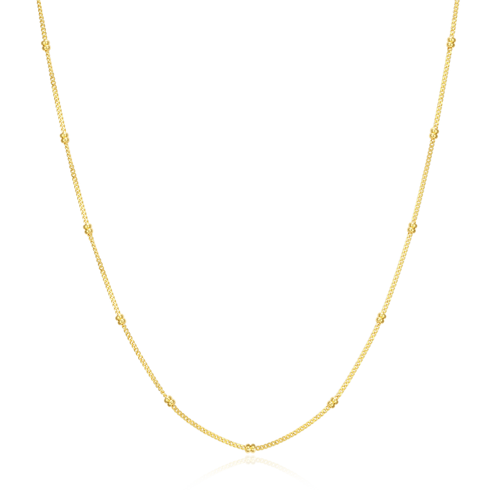 Gold chain necklace with small gold stationed beads on a white background